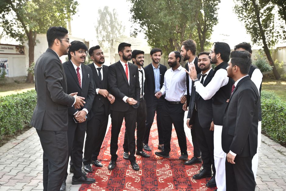 A group of men in formal attire conversing outdoors on a sunny day.