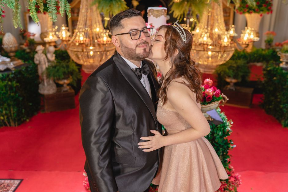 A couple dressed elegantly enjoys a luxurious indoor celebration, surrounded by ornate decor and vibrant lighting.