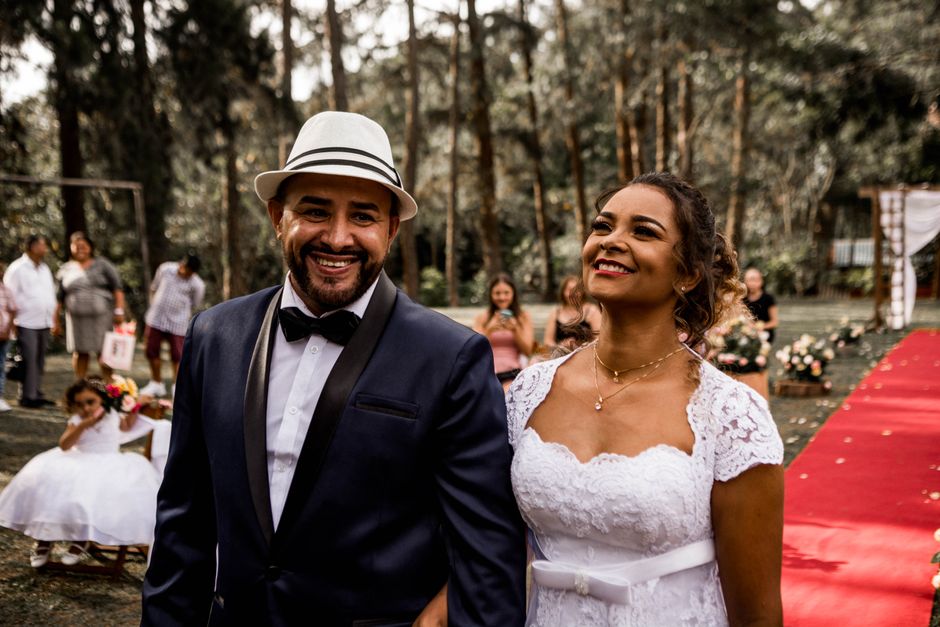 A happy bride and groom walking down the aisle outdoors during their wedding ceremony.
