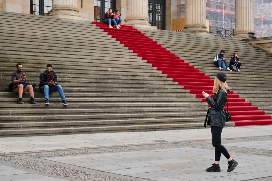 People gather on red-carpeted steps in Berlin, Germany, capturing city vibes.